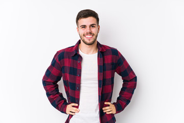 Young caucasian man posing in a white background isolated confident keeping hands on hips.