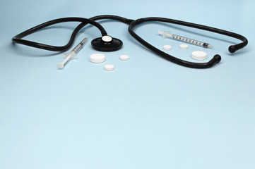 Stethoscope, pills and syringes, attributes medical, health care ,cardiac care on above blue background copy space