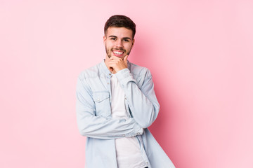 Young caucasian business man posing in a white background isolated smiling happy and confident, touching chin with hand.< mixto >