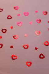 Red heart shaped confetti on pale pink background. Love and valentine concept. Selective focus. 