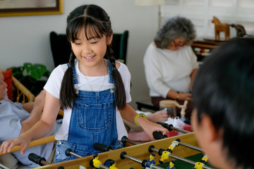 Fototapeta premium Soft blur of little girl has fun with table soccer while grandparent enjoy use mobile phone as background.