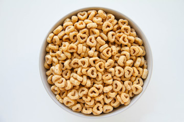 Bowl of whole grain oat cereal on a white background, top view. Heart shapes cereal. 