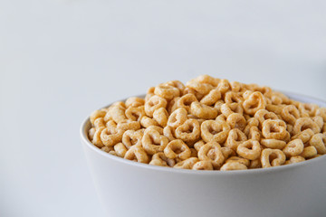 Bowl of whole grain oat cereal on a white background, back view. Heart shapes cereal. 
