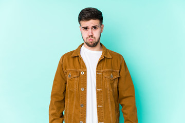 Young handsome man blows cheeks, has tired expression. Facial expression concept.