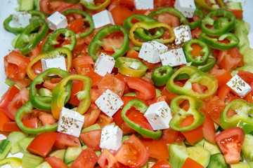 closeup of a salad made of tomatoes, cucumbers, peppers and cheese with spices