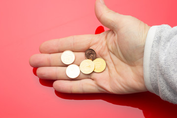 Euro coins in the hand of an adult person, on colored background