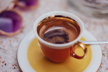 Eine orangene Espressotasse auf einem Tisch in einem Café bei warmem Sonnenlicht im Sommer