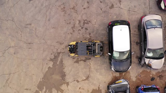 Forklift transporting a Car at a Salvage Car parts and Vehicles lot, Aerial view.