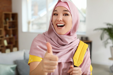 Female Muslim student showing thumb-up at home