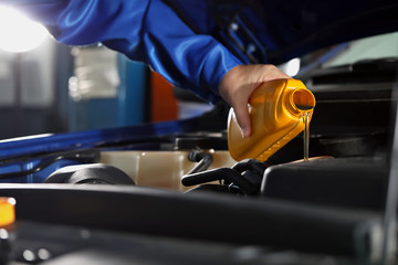 Fototapeta premium Male mechanic refilling car oil in service center