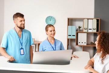 Male and female receptionists working at desk in clinic
