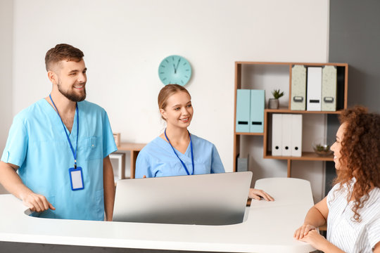 Male and female receptionists working at desk in clinic