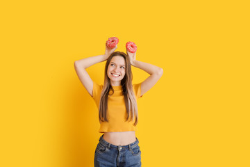 Funny young woman with tasty donuts on color background
