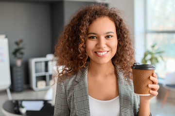 Young African-American businesswoman with coffee in office