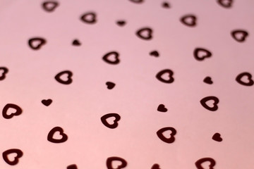 Red heart shaped confetti on pale pink background. Love and valentine concept. Selective focus. 