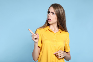 Young beautiful girl showing by finger on blue background