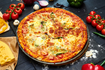Pizza with mozzarella cheese, tomatoes, mushrooms, pepper on a dark wooden background.