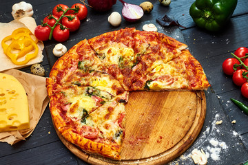 Pizza with mozzarella cheese, tomatoes, mushrooms, pepper on a dark wooden background.