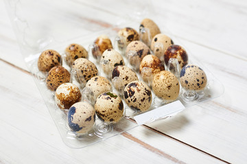 quail eggs in a tray on a light wooden background.