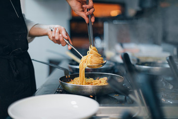 Chef preparing a pasta dish in traditional Italian restaurant kitchen