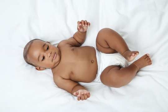 American baby girl lying on white bed