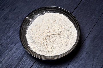 Plate with flour on a dark background.