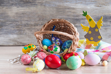 Easter holiday still life. Wicker basket with easter eggs, willow twigs, checkered napkin on old wooden background