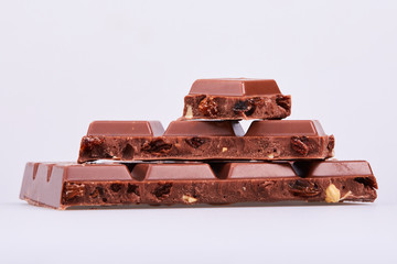 Milk chocolate. Chunks of chocolate with hazelnuts and raisins isolated on white background. 