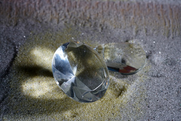 Artificial diamonds lying in the sand photographed in the studio with flash light