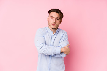 Young caucasian man posing in a pink background isolated frowning face in displeasure, keeps arms folded.