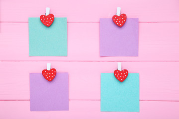 Paper sticky notes with clothespins on pink wooden table