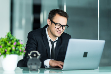 Handsome young business man in suit in office with laptop.