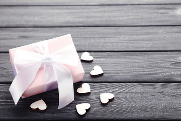 Gift box with ribbon and hearts on black wooden table