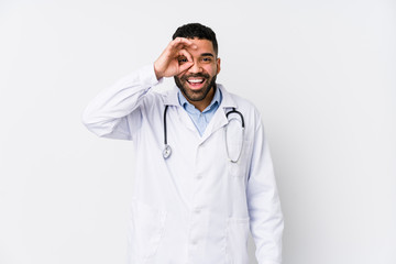 Young arabian doctor man isolated excited keeping ok gesture on eye.