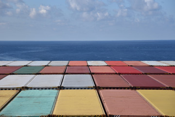 Obraz premium Containers loaded on the cargo container ship, she is sailing through calm blue sea.