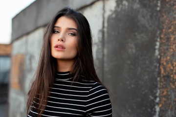 Fototapeta premium Beauty frontal portrait of a cheerful girl with straight brunette hair, dressed in modern clothes, with makeup.
