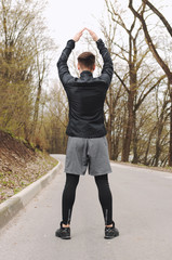 Sport man stretching at the park, doing exercises.