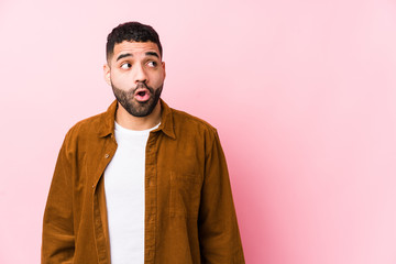 Young latin man against a pink background isolated being shocked because of something she has seen.