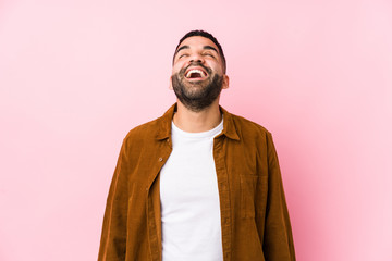 Young latin man against a pink background isolated relaxed and happy laughing, neck stretched showing teeth.