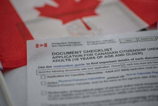 Document check list application for canadian citizenship next to Canadian flag, close up view.