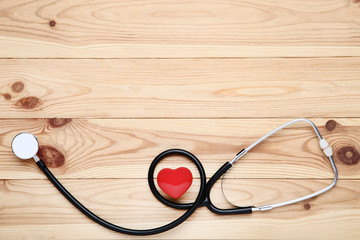 Stethoscope with red heart on brown wooden table