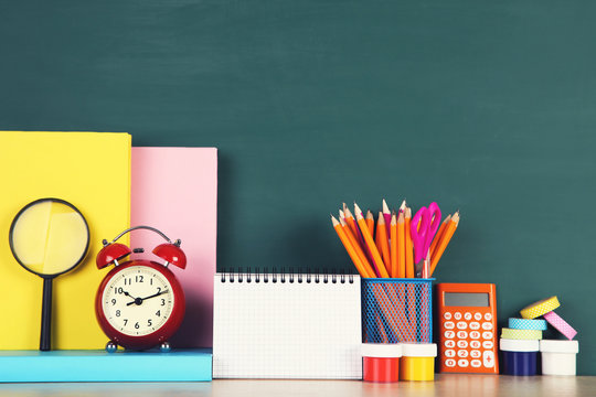 School supplies with red alarm clock on green background