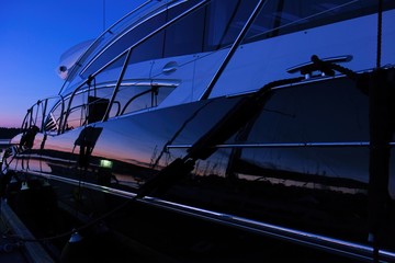 Yacht at the marina captured during a blue hour with setting sun coloring the horizon and...