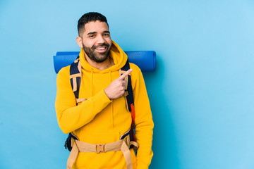 Young arabian traveler backpacker man isolated smiling and pointing aside, showing something at blank space.