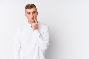Young caucasian man on white background looking sideways with doubtful and skeptical expression.