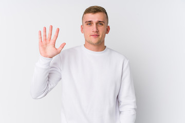 Young caucasian man on white background smiling cheerful showing number five with fingers.