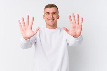 Young caucasian man on white background showing number ten with hands.