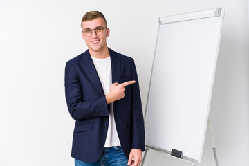 Young coaching man showing a white board smiling and pointing aside, showing something at blank space.