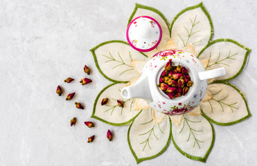 Obraz na płótnie Canvas Top view of a cup of tea with dried roses 