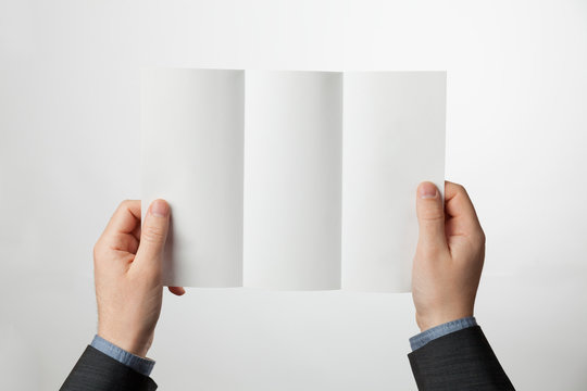Tri-fold paper brochure in hands. Z-fold design blank for marketing or advertising.